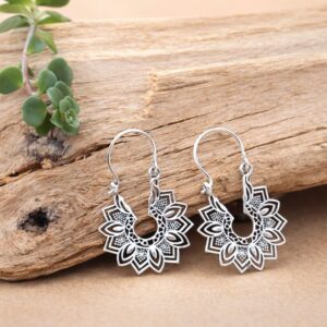 Boucles d'oreilles mandala en laiton posées sur du bois brut.