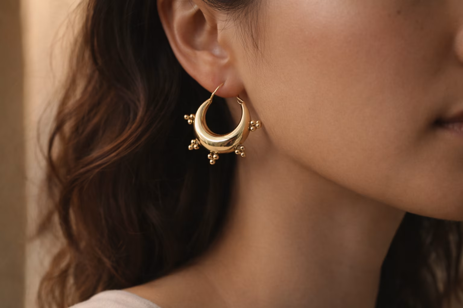 solia-boucles-oreilles-ethniques-laiton Paire de boucles d'oreilles créoles épaisses en laiton doré de style ethnique, posées sur un bois brut.